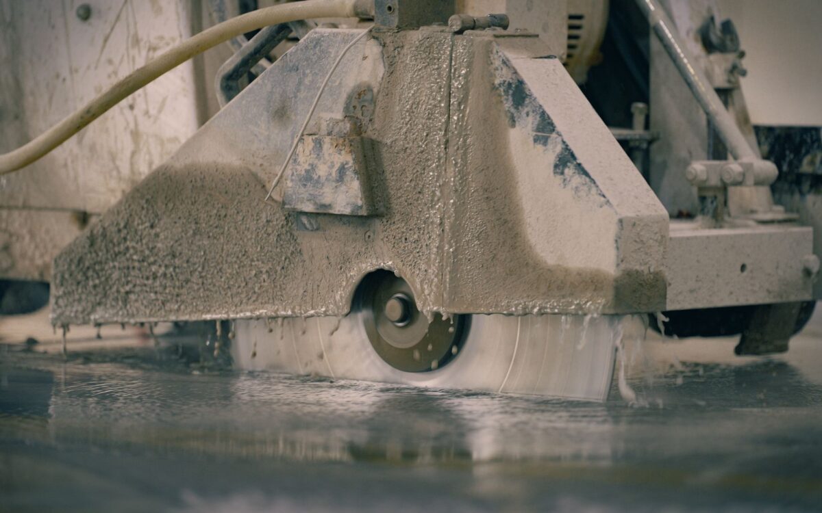Close-up of a concrete saw cutting a floor, showcasing industrial machinery in action.