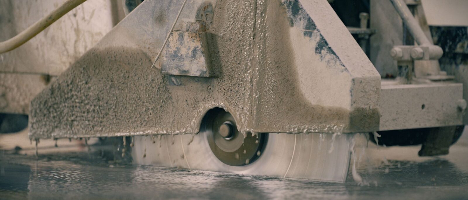 Close-up of a concrete saw cutting a floor, showcasing industrial machinery in action.
