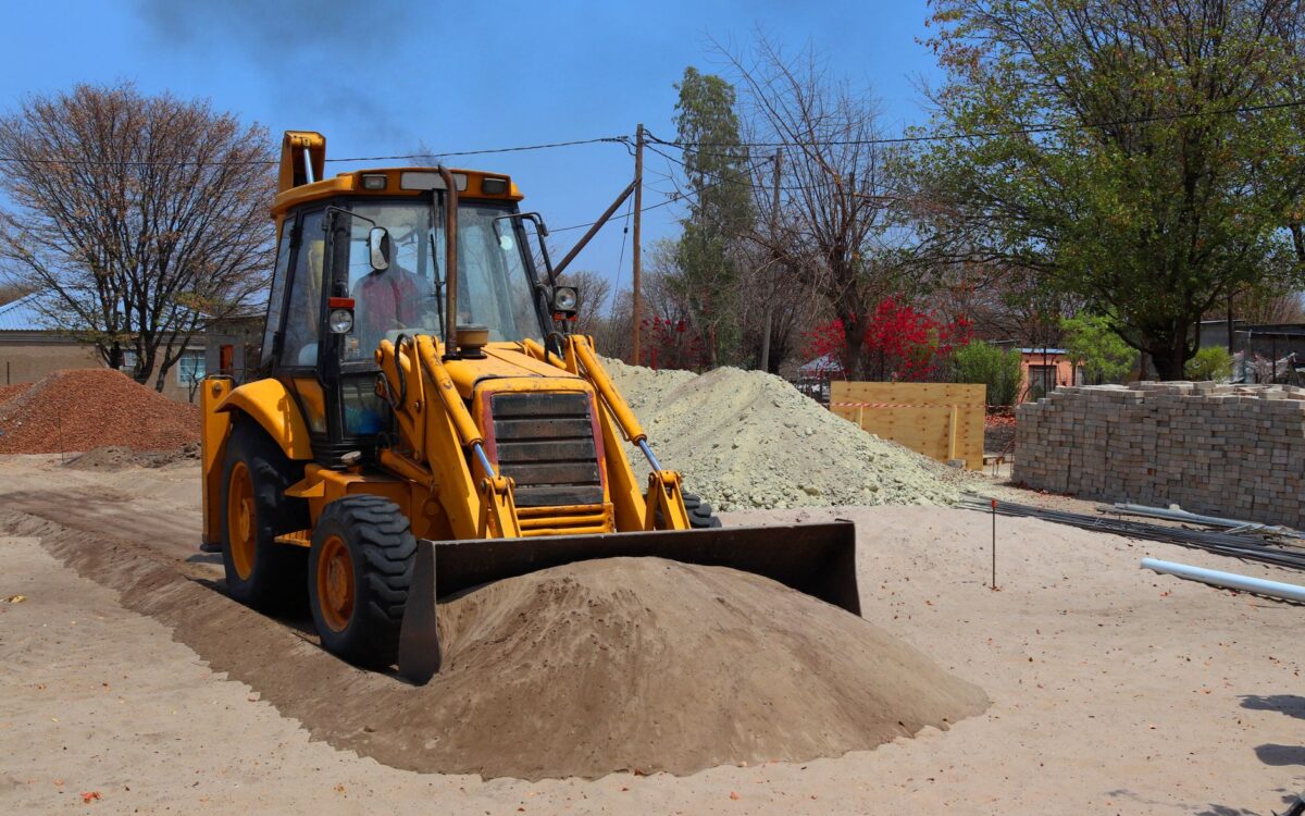 Utah construction site with yellow excavator and loader equipment for rental vs buying cost comparison