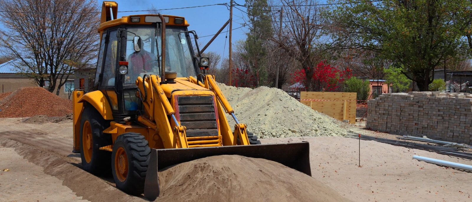 Utah construction site with yellow excavator and loader equipment for rental vs buying cost comparison