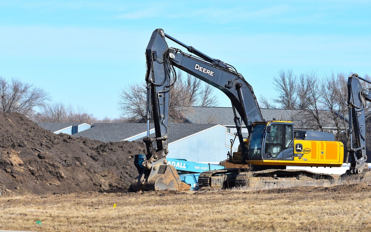 Yellow excavator rental on active Utah construction site with operator digging foundation