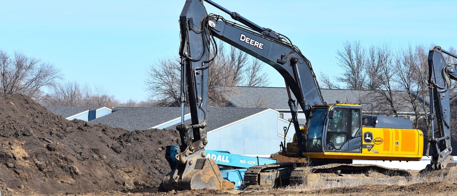 Yellow excavator rental on active Utah construction site with operator digging foundation