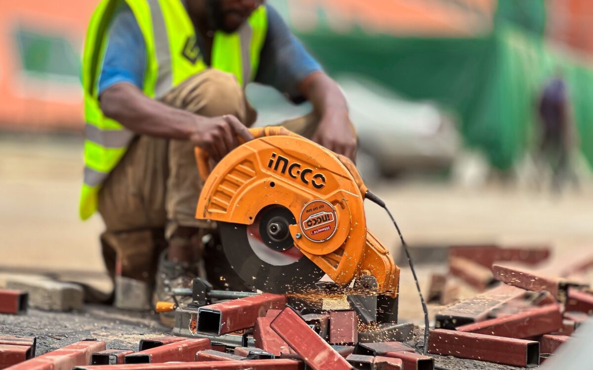 Worker using circular saw to cut metal on a construction site.