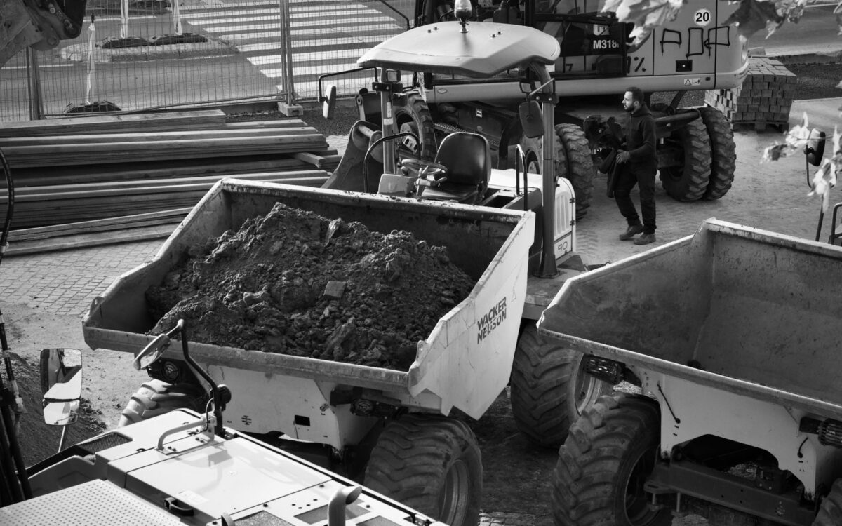 Black and white image of a construction site with machinery and a worker.