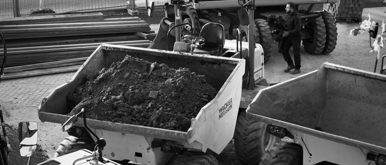 Black and white image of a construction site with machinery and a worker.