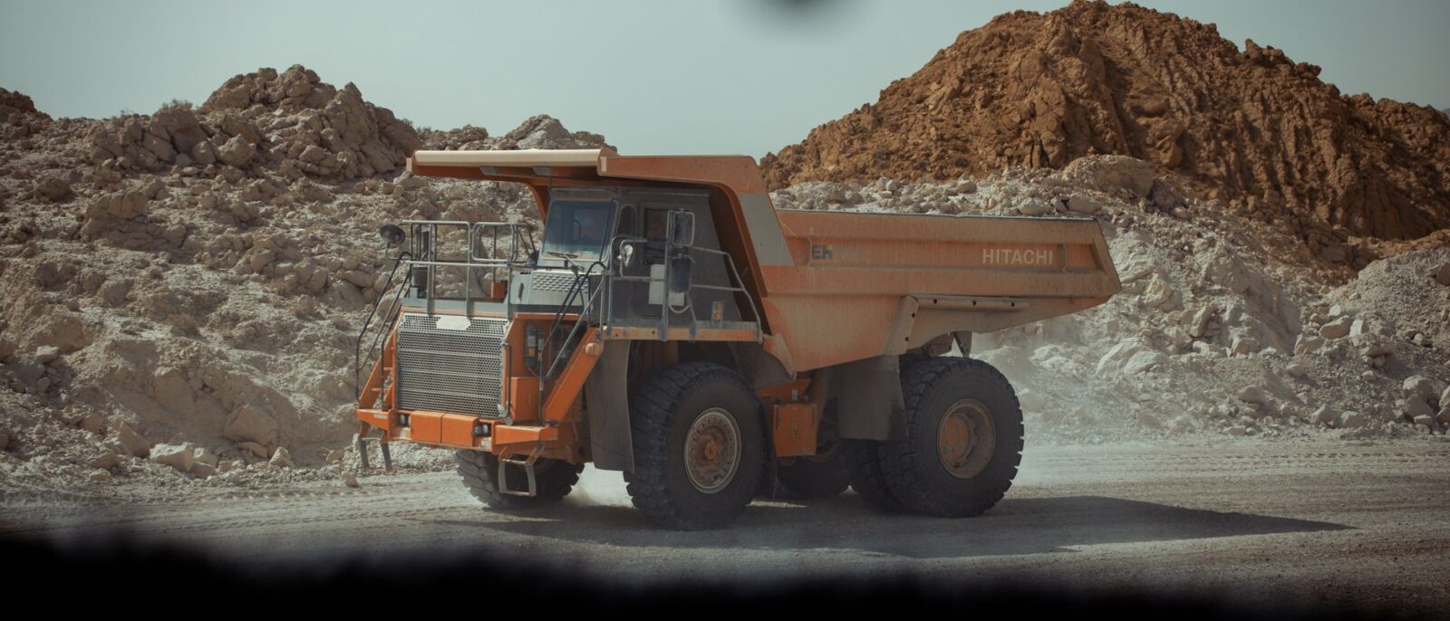 A large dump truck operates in a dusty quarry in Biskra, Algeria.