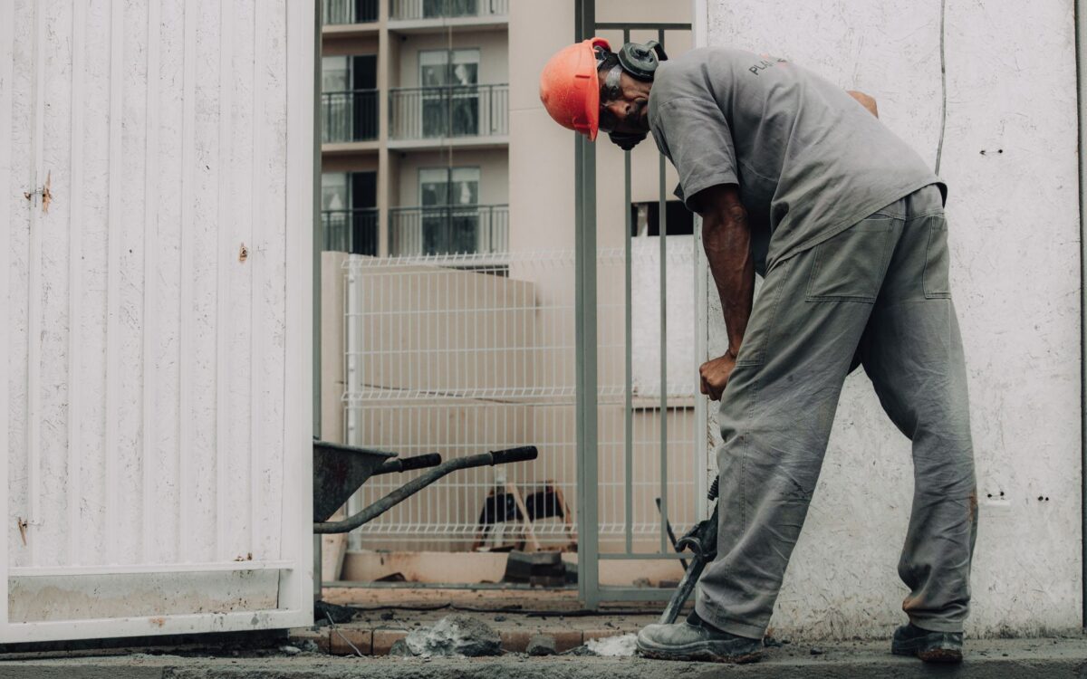Man in hard hat operating a jackhammer on an outdoor construction site.