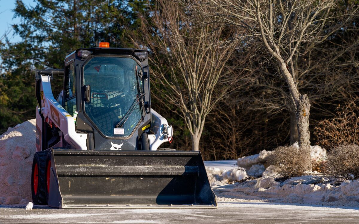 A skid steer loader clearing snow on a bright winter day outdoors in Virginia, USA.